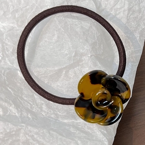 Macro shot of camellia hair tie with tortoiseshell resin flower on white paper