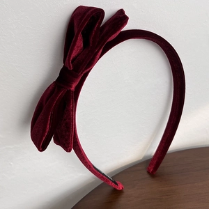 Close-up of wine red velvet headband with a stylish retro bow design and soft fabric texture