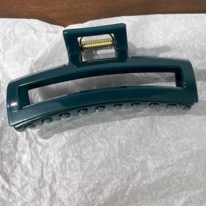Détail d'une grande pince à cheveux rectangulaire vert foncé avec ressort en métal doré