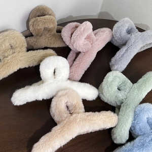 Detail view of plush hair claw clips in various Morandi colors on a dark wooden surface
