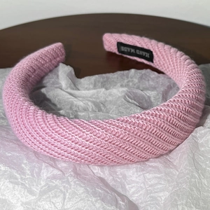 Vue détaillée du serre-tête rose en tricot épais avec étiquette Hand Made sur bois