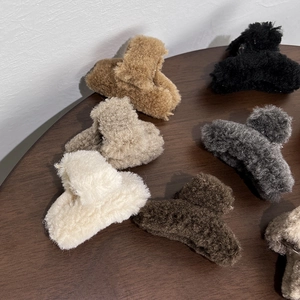 Detailed macro view of assorted plush hair clips in neutral colors on a wooden surface