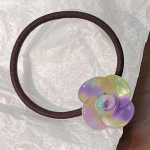 Detailed close-up of a brown elastic hair tie with a colorful resin floral ornament