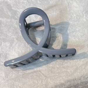 Close-up of a dusty blue minimalist hair claw clip with crossed design and metal spring