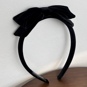 Detail of handmade black velvet headband featuring double bow design and textile label