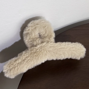 Detail of soft cream plush hair claw clip with a focus on fluffy faux fur texture