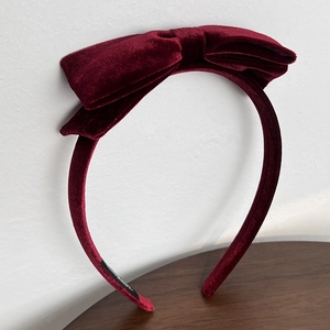 Detail view of the wine red velvet bow headband showing handmade label and fabric texture