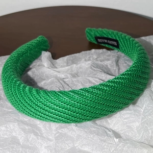 Détail du bandeau tricoté vert avec étiquette fait main et texture tressée