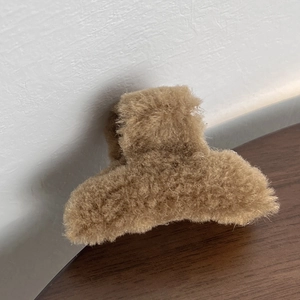 Close-up of a small plush hair claw clip in light brown faux fur with soft texture