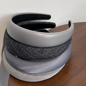 Détail de quatre serre-têtes gris aux textures en cuir, velours et maille tressée