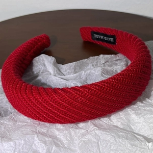 Détail du serre-tête en maille rouge torsadée avec étiquette faite à la main