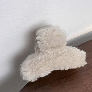 Detailed close-up of a plush beige hair claw clip with soft faux fur texture for winter