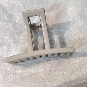 Close-up of minimalist greige rectangular hair claw clip with glossy finish and metal spring