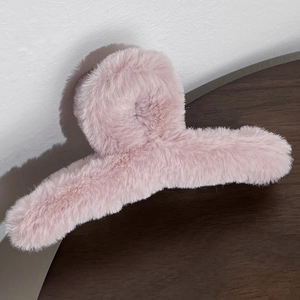 Macro shot of a long plush hair claw clip in soft pink faux fur for autumn winter styling