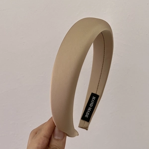Vue détaillée de la texture du serre-tête en satin champagne avec son étiquette fait main