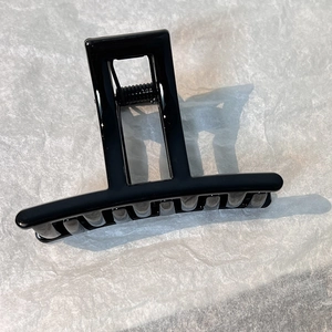 Detail view of large black square hair claw clip with glossy resin finish and metal spring
