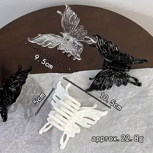 Elegant butterfly hair claw clips in black and white acrylic finish on a wooden table
