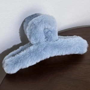 Macro shot of light blue plush hair claw clip with soft faux fur texture on wood
