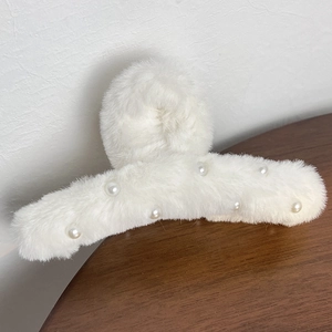 Close-up of white plush hair claw clip with pearl accents for autumn and winter styles