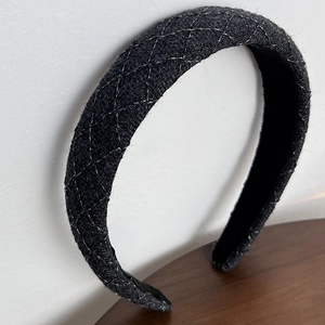 Détail d'un serre-tête vintage en tweed noir avec matelassage argenté et rembourrage