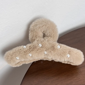 Detail of plush khaki hair claw clip with white pearl accents on fuzzy faux fur texture