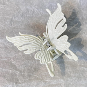 Detail view of cream butterfly hair claw clip with bionic wing texture and metal spring