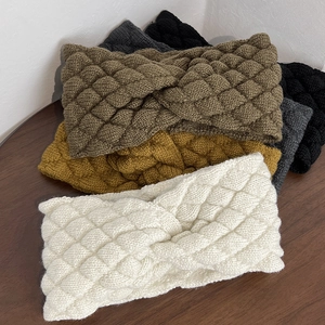 Close-up of five colorful knitted twist headbands with thick diamond texture on wood