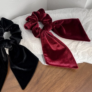Close-up of elegant black and burgundy velvet bow scrunchies with long ribbons