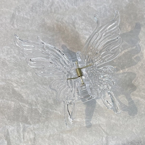 Close-up of butterfly hair claw clip with golden metal spring and clear resin texture