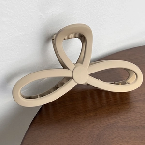 Detail view of large matte beige butterfly hair claw clip with strong metal spring