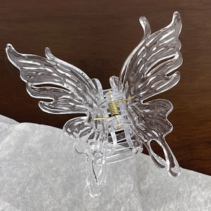 Macro detail of transparent butterfly hair claw clip with golden metal spring