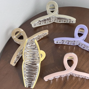 Close-up of 13cm large matte hair claws in five pastel colors on a wooden table