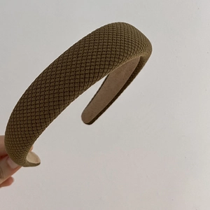Macro view of olive green wide padded headband showing textured quilted fabric