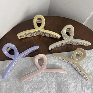 Detailed view of large matte hair claws in five colors on a wooden and textured background