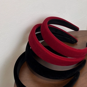 Close-up of thick velvet headbands in red and black stacked on a wooden surface