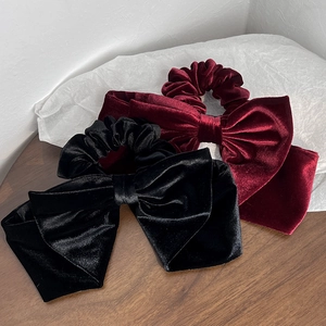 Close-up of elegant velvet bow scrunchies in black and burgundy on a wooden surface