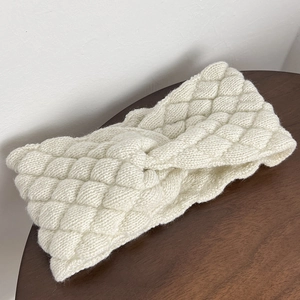 Close-up of beige knitted headband with diamond pattern texture and elegant twist knot detail