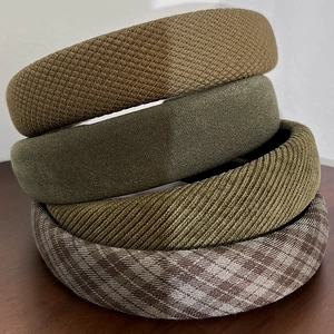 Close-up of stacked fabric headbands in green plaid and waffle textures on wood