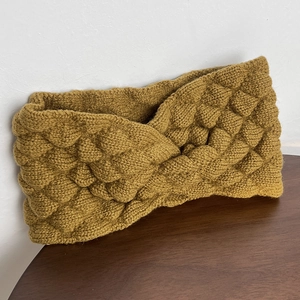Detail of mustard yellow knitted headband showing thick textured bubble weave and twist design