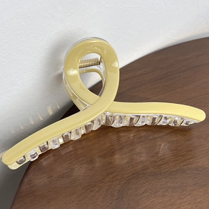 Macro detail of a 13cm yellow and clear twisted claw clip with a glossy acrylic finish
