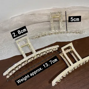 Grandes pinces à cheveux dorées avec perles et strass sur fond bois et blanc élégant