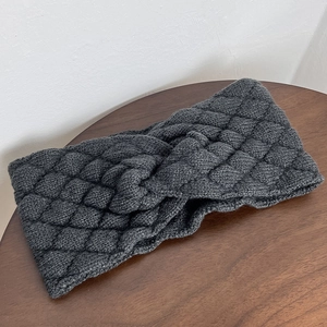 Detail of cross-knot design on dark grey chunky knit headband with diamond pattern texture