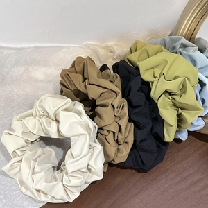 Detailed view of five oversized matte scrunchies in earthy tones on a rustic background