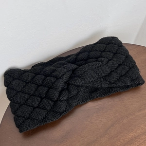 Detail view of black chunky knit headband featuring cross knot and bubble texture