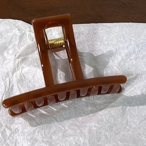 Detail view of large amber resin hair claw clip with glossy finish and metal spring