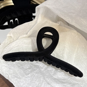 Gros plan sur la pince à cheveux noire floquée avec design torsadé sur papier blanc