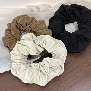 Detailed close-up of brown, black and cream fabric scrunchies on a wooden table