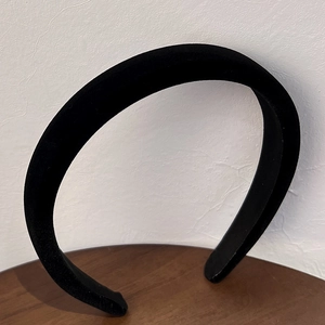 Detail view of wide black velvet headband with a soft texture and retro padded style