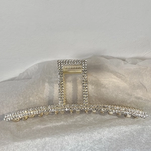 Détail d'une pince à cheveux rectangulaire dorée ornée de plusieurs rangées de strass
