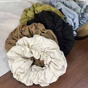 Close-up of five earth-tone pleated fabric scrunchies in minimalist French style